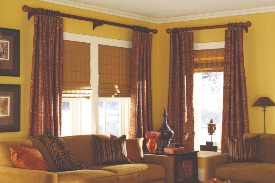 A yellow living room with white crown molding and gold Roman window shades